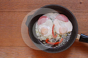 Breakfast in the pan. Eggs and sausage in the shape of a face on a wooden background