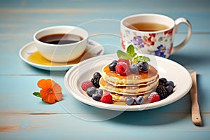 breakfast pancakes with maple syrup and fresh berries on ceramic plate