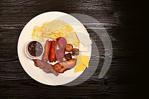 Breakfast plate with crepe, jam, fried sausages, bacon, cherry tomatoes and cheese variations.