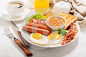 breakfast with plate of fried eggs  bacon  beans  sausages  toasts and tomatoes