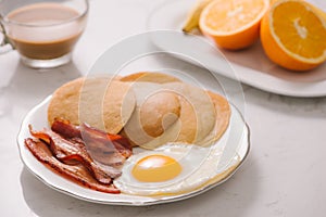 Breakfast plate with pancakes, eggs, bacon and fruit.