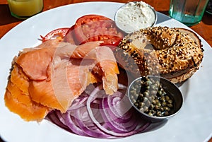 Breakfast plate of smoked salmon, red onions, bagel, capers, tomato and cream cheese