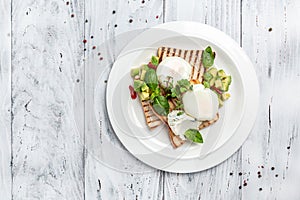 Breakfast. Poached eggs on toasted bread with avocado in plate on wooden background. banner, menu, recipe place for text, top view