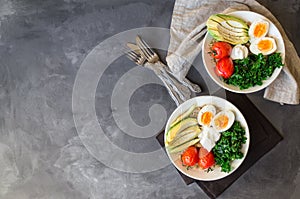 Breakfast quinoa bowls with baked tomatoes, avocado, kale, boiled eggs and greek yogurt