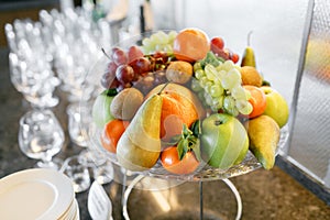 Breakfast in restaurant of hotel. Plate with fruits and berries on a smorgasbord. Many wineglasses. in the background