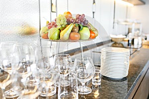 Breakfast in restaurant of hotel. Plate with fruits and berries on a smorgasbord. Many wineglasses. in the background