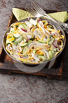 Breakfast salad of shredded chicken, cucumber, red onion and chopped egg pancakes closeup on the plate. Vertical