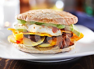 Breakfast sandwich with egg, bacon, avocado and vegetables