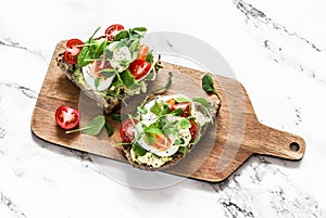 Breakfast sandwiches with multigrain bread, avocado, boiled egg, microgreens, cherry tomatoes and homemade mayonnaise sauce on a