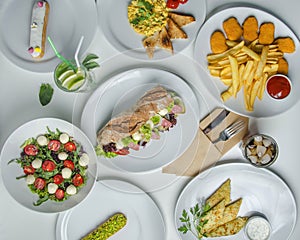 Dishes on a white table with white plates. Top view