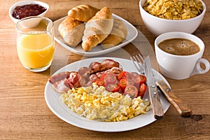 Breakfast with scrambled eggs, bacon, tomatoes,coffee,orange juice ,croissant and corn flakes