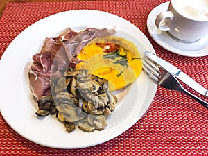 Breakfast with scrambled eggs, champignons and meat