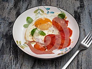 Breakfast with scrambled eggs and fresh tomatoes on a colored plate