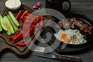 Breakfast-scrambled eggs, garlic sauce, tomatoes, cucumbers, bacon and coffee. Top view