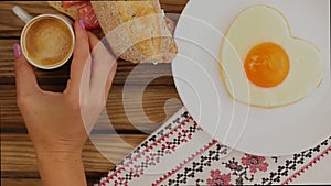 Breakfast serving: fried egg in the shape of a heart, sandwich and cup of coffee