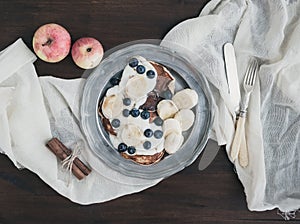 Breakfast set on dark wooden desk: apple and cinnamon pancakes