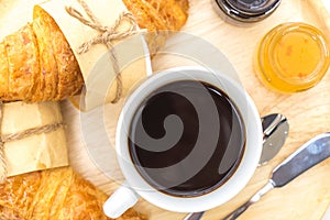 Breakfast set have a tray of coffee, croissant, jams