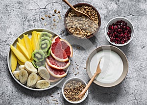 Breakfast set table - fresh tropical fruits, greek yogurt, granola on a gray background, top view. Delicious healthy diet food