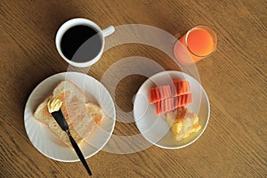 Breakfast set, toast with butter, fresh fruit, coffee, orange juice.