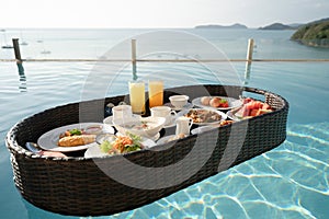 Breakfast set in tray in swimming pool, floating breakfast in tropical resort villa with ocean view