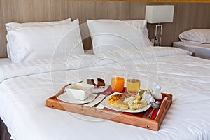 Breakfast set in wooden tray serving on bed