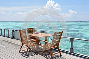 Breakfast setup with wooden tables and chairs at the restaurant near the ocean