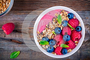 Breakfast smoothie bowl with granola, fresh raspberry, blueberry, chia seeds and mint