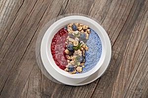 Breakfast smoothie bowl with granola on wooden background