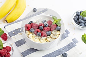 Breakfast smoothie with granola, yogurt, fresh raspberries, blueberries, bananas, coconut flakes, Chia seeds and mint.