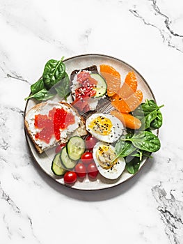 Breakfast, snack, tapas plate - sandwiches with red caviar, salmon, cream cheese, vegetables, spinach, boiled egg on a light