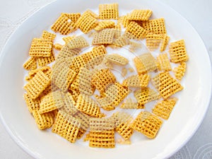 Breakfast square cornflakes with milk in a bowl