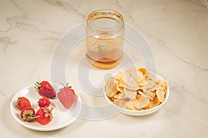 breakfast with strawberry, flakes and honey/healthy concept: breakfast with strawberry, flakes and honey on a white marble table