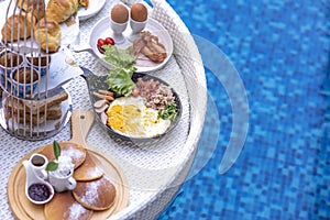 Breakfast in swimming pool, floating breakfast in villa resort. Relaxing in calm pool water, healthy breakfast and tropical fruit