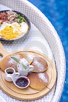 Breakfast in swimming pool, floating breakfast in villa resort. relaxing in calm pool water, healthy breakfast and tropical fruit