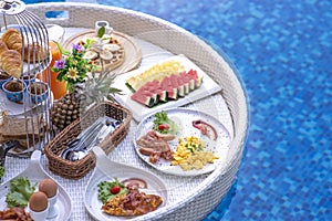 Breakfast in swimming pool, floating breakfast in villa resort. relaxing in calm pool water, healthy breakfast and tropical fruit