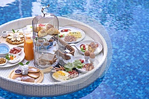 Breakfast in swimming pool, floating breakfast in villa resort. relaxing in calm pool water, healthy breakfast and tropical fruit