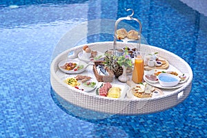 Breakfast in swimming pool, floating breakfast in villa resort. relaxing in calm pool water, healthy breakfast and tropical fruit