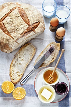 Breakfast table. Bread and boiled eggs, butter and honey with marmalade,