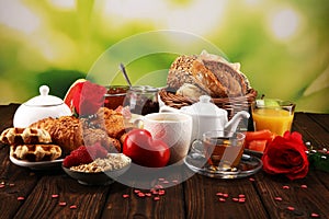 Breakfast on table with bread buns, croissants, coffe and juice on valentines day