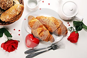 Breakfast on table with bread buns, croissants, coffe and juice on valentines day