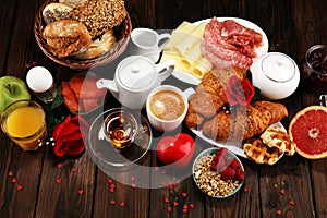 Breakfast on table with bread buns, croissants, coffe and juice on valentines day