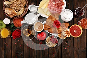 Breakfast on table with bread buns, croissants, coffe and juice on valentines day