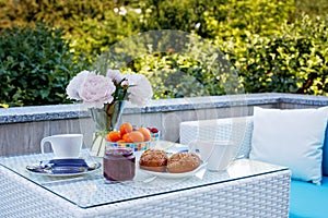Breakfast table with bread, fresh fruits and strawberries and coffee served on balkony terrace or hotel on summer