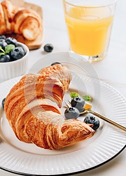 Breakfast table with croissants, coffee, orange juice and blueberries