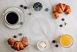 Breakfast table with croissants, coffee, orange juice and blueberries