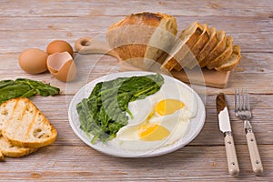 Breakfast on the table with fried eggs and spinach. Closeup view