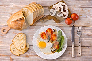 Breakfast on the table with fried eggs and spinach, tomatoes and mushrooms. Flat lay