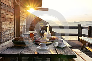 Breakfast table in rustic wooden terace patio of a hut hutte in Tirol alm at sunrise