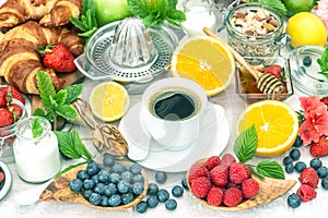 Breakfast table setting with coffee, croissants, granola, honey.