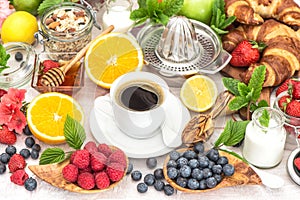 Breakfast table setting with coffee, croissants, muesli, honey.